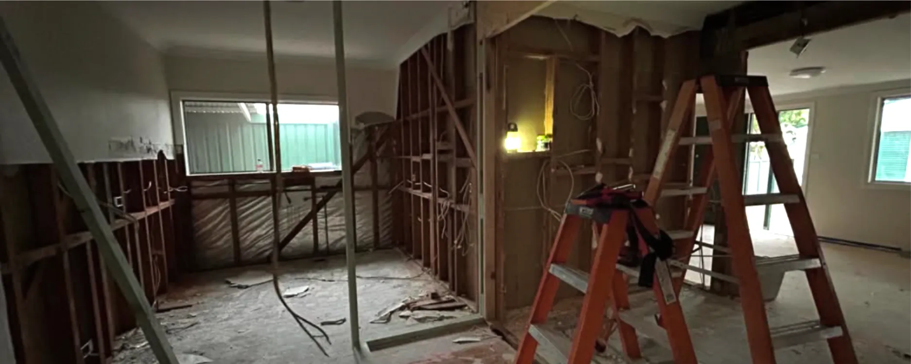 A room stripped back to the timber frame during a renovation, with a ladder and loose cabling